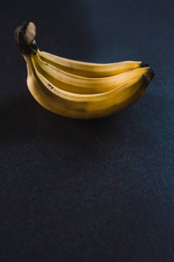 alan sığ derinlikte çekilen koyu arka plan üzerinde üç muz