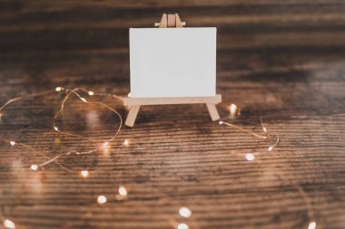 ahşap masa üzerinde peri ışıkları ile çevrili siyah tuval minyatür