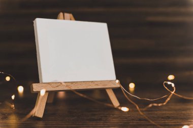 ahşap masa üzerinde peri ışıkları ile çevrili boş tuval minyatür