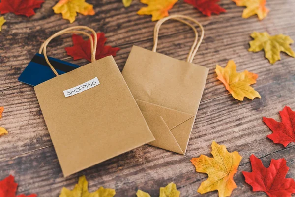 Bolsa de compras en mesa de madera rodeada de hojas de otoño , — Foto de Stock