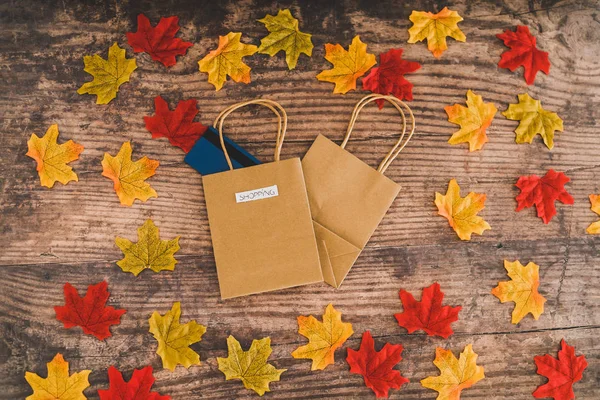 Shopping bag with payment card on wooden table surrounded by aut — Stock Photo, Image