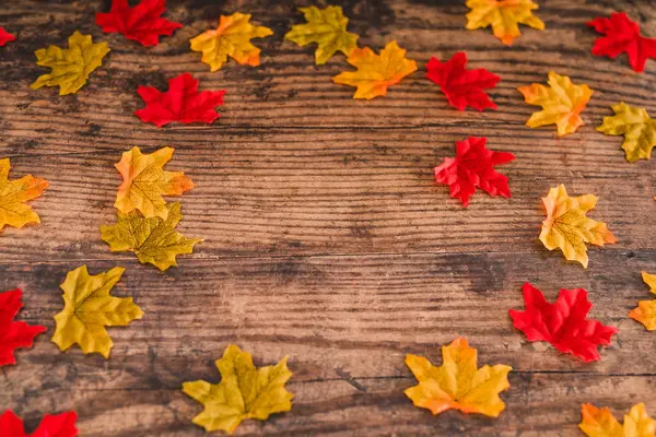 Wooden desk with frame of autumn leaves and copyspace — Stock Photo, Image