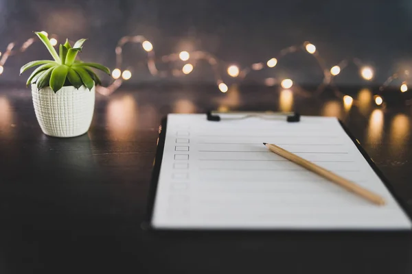 clipboard with blank list with cases to tick off on wooden desk