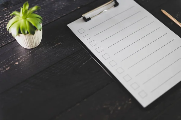 clipboard with blank list with cases to tick off on wooden desk