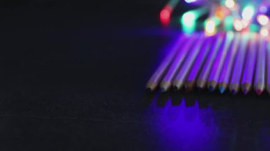 renkli kalemler psychedelic çok renkli ışık bokeh ve kamera yatay soldan sağa kaydırma ile koyu masa üzerinde dizilmiş