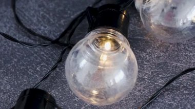 yaratıcılık ve iyi fikirlerin metaforu olarak karanlık masada parlayan başkalarının grup önünde izole bir benzersiz ampul, dikey kaydırma kamera