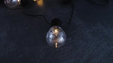 yaratıcılık ve iyi fikirlerin metaforu olarak karanlık masada parlayan başkalarının grup önünde izole bir benzersiz ampul, dikey kaydırma kamera