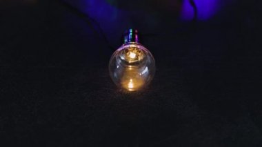 büyüteç analiz (en iyi fikir değerlendirme metaforu), kamera yatay kaydırma ile karanlık masada parlayan başkalarının grup önünde izole bir benzersiz ampul