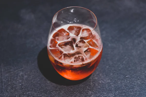 Bicchiere da cocktail spritz arancione con ghiaccio su cemento scuro — Foto Stock