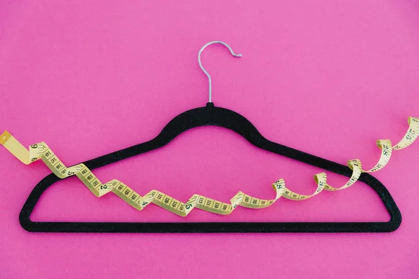 Вішалка для одягу з мірною стрічкою на рожевому фоні — стокове фото