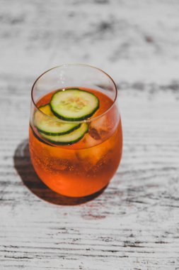 Buz ve salatalık dilimli turuncu kokteyl.