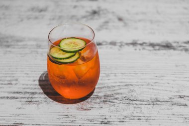 Buz ve salatalık dilimli turuncu kokteyl.