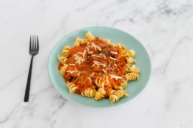 Domates soslu ve rendelenmiş peynirli makarna tabağı.