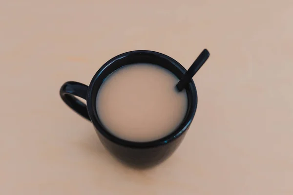 Té chai con leche en taza negra sobre mesa de madera del mismo colo — Foto de Stock