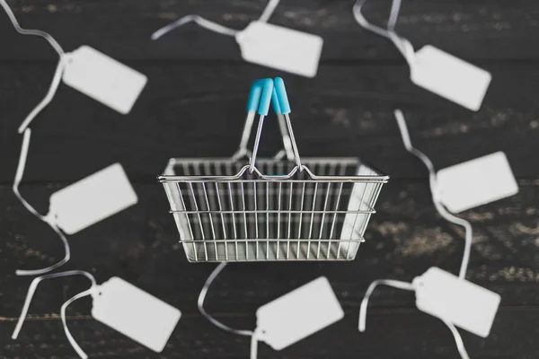 Shopping basket surrounded by price tags — Stock Photo, Image