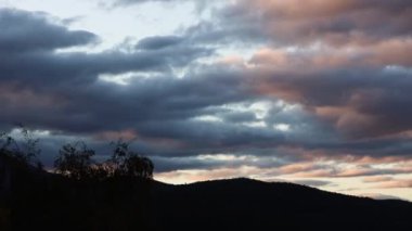 Gün batımı bulutlarının zamanı geçiyor ve hava, dağların üzerinden alacakaranlıkta değişiyor. Tazmanya 'da Wellington Dağı' nda çekilen Kunanyi de buna dahil.