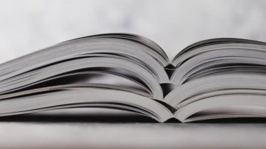 Eğitim ve kendini geliştirme konsepti, göz hizasından çekilen ve yüzeysel alan derinliği ve yatay olarak çekilen kameraların üzerine yığılmış bir yığın açık kitap.