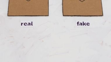 Güvenilir ve sahte e-postalar ya da çevrimiçi dolandırıcılık konsepti, e-posta zarfları sahte etiketli simgeler ve dikey olarak görüntülenen kamera