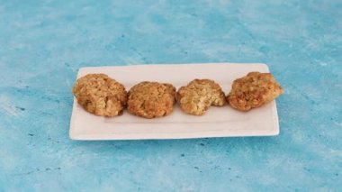 sağlıklı bitkisel yemek tarifleri konsepti, vejetaryen badem ve yulaf kurabiyeleri ve bir tanesini alıp bir ısırıkla geri yerleştirmek.