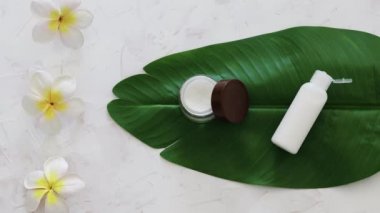 Sert kimyasallar olmadan vegan doğal güzelliği, yüz kremi tenceresi ve tropik yeşil yapraklı vücut losyonu monoi çiçekleri ve kamera çözücü.