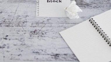 yaratıcı blok veya ilham eksikliği kavramsal video, tahta masa üzerinde kağıt parçası Yazar Blok metin ile çevrili boş notlar ve yanında bükülmüş kağıt top ve kamera dikey dönüm