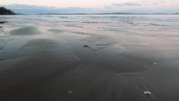 crépuscule sur la plage en Tasmanie par une journée d'automne fraîche avec des vagues océaniques se déplaçant vers la caméra, prise de vue de basse perspective à Kingston Beach près de hobart 