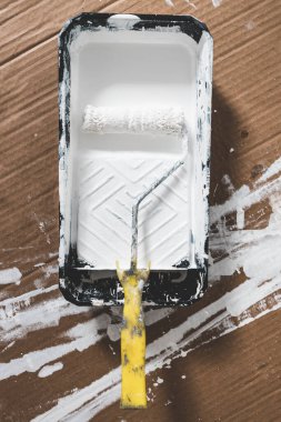 DIY ve ev geliştirme konsepti, üzerinde beyaz parlak boya ve boya rulosu olan boya tepsisi