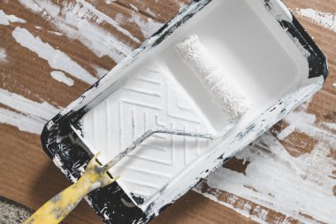 DIY ve ev geliştirme konsepti, üzerinde beyaz parlak boya ve boya rulosu olan boya tepsisi