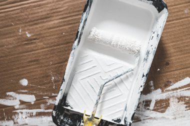 DIY ve ev geliştirme konsepti, üzerinde beyaz parlak boya ve boya rulosu olan boya tepsisi