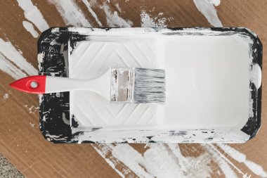 DIY ve ev geliştirme konsepti, üzerinde beyaz parlak boya ve boya fırçası olan boya tepsisi