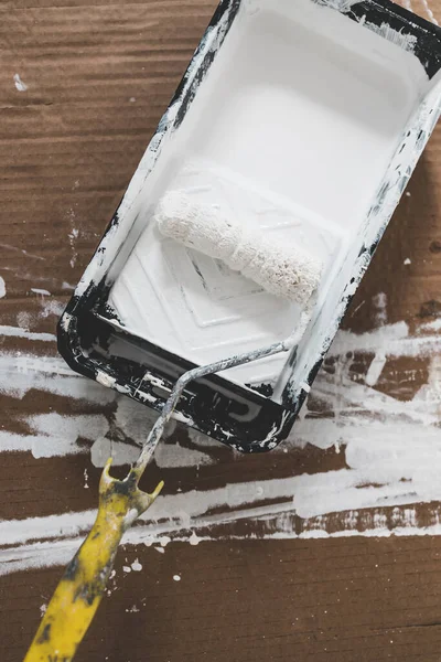 DIY and home improvement concept, paint tray with white glossy paint and paint roller on it
