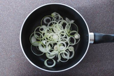 Basit gıda malzemeleri konsepti, tencerenin içinde sotelenmeye hazır soğan halkaları.