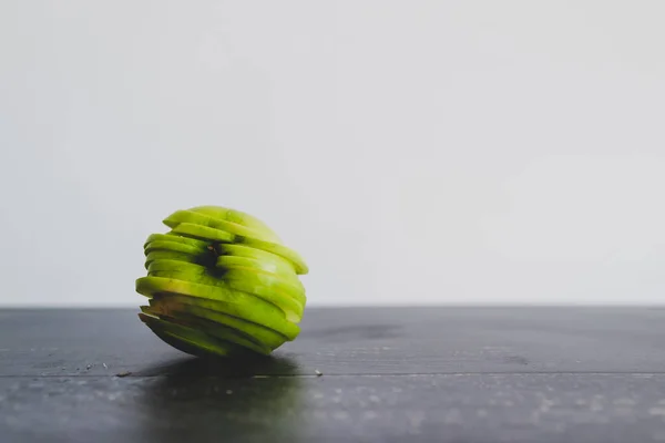 healthy plant-based food ingredients concept, green apple cut into thin equal slices stacked to maintain its original shape
