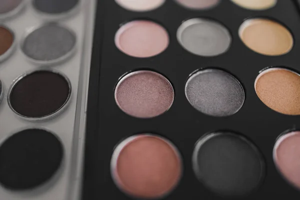 cosmetics and beauty industry concept, close-up of two similar eyeshadow palettes with neutral nude tones next to each other metaphor of competition