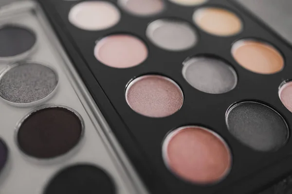 cosmetics and beauty industry concept, close-up of two similar eyeshadow palettes with neutral nude tones next to each other metaphor of competition