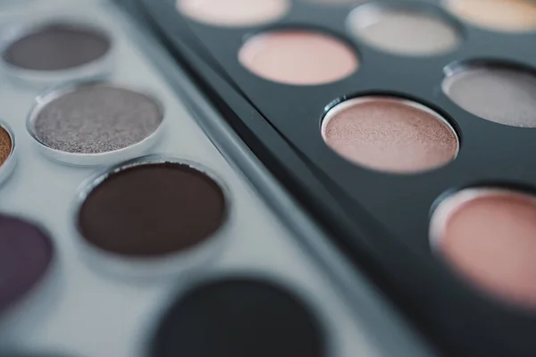 cosmetics and beauty industry concept, close-up of two similar eyeshadow palettes with neutral nude tones next to each other metaphor of competition