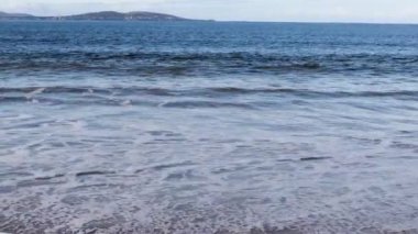 Tazmanya, Avustralya 'da kumsalda dalgalar kameraya doğru ilerliyor ve sonra aşağı vuruyor.