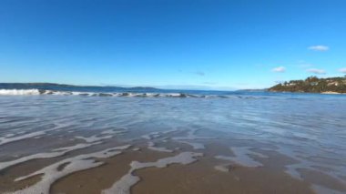 Tazmanya, Avustralya 'da kumsalda dalgalar kameraya doğru ilerliyor ve sonra aşağı vuruyor.