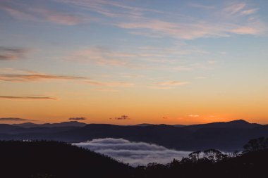 Tazmanya, Avustralya tepelerinde yuvarlanan güzel bulutlarla gün doğumu gökyüzü