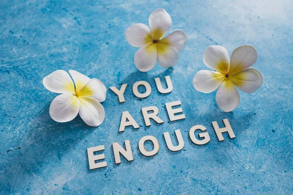 mental health and self-worth concept, You are enouugh text with flowers and blue background