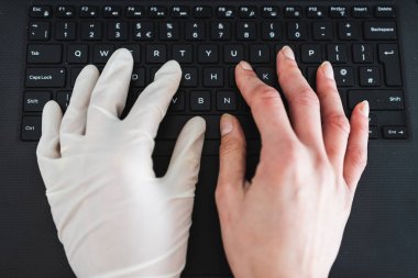 Covid-19 virüsünün salgınından sonra güvende olmak, iş yerinde paylaşılan bilgisayar klavyesine tek kullanımlık eldiven takmak, potansiyel olarak enfekte olmuş yüzeylerle temas kurmamak ve diğer elini eldivensiz kullanmak.