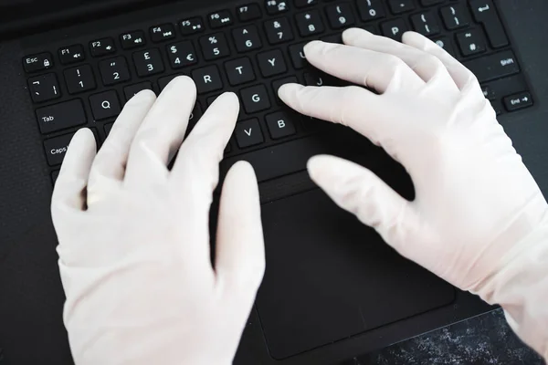 the new normal after thecovid-19 virus pandemic outbreak, hands typing on shared computer keyboard at work wearing disposable gloves to avoid contact with potentially infected surfaces