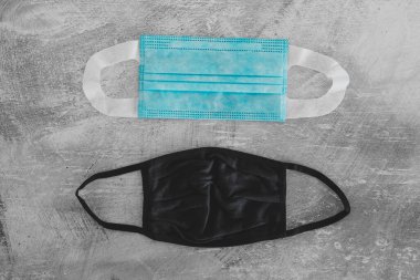 Covid-19 virüs salgınından sonraki yeni normal. Beton yüzeyde cerrahi maske, kumaş ve inşaat maskeleri de dahil olmak üzere farklı yüz maskeleri.