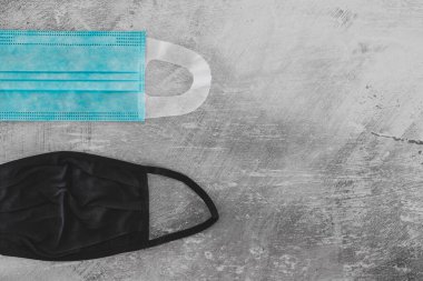 Covid-19 virüs salgınından sonraki yeni normal. Beton yüzeyde cerrahi maske, kumaş ve inşaat maskeleri de dahil olmak üzere farklı yüz maskeleri.