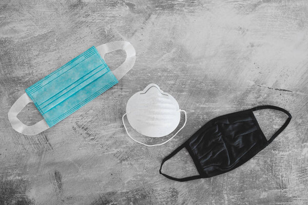 новая норма после вспышки вируса ковид-19, различные маски для лица, включая хирургические маски, ткани и строительные на бетонной поверхности