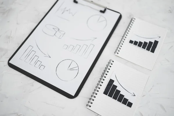 business analysis and statistics concept, positive and negative trends on graphs on notebooks next to clipboard with mixed charts