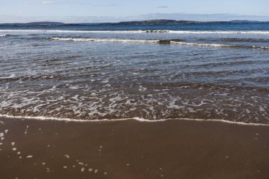 Tazmanya 'da el değmemiş bir sahil derin mavi okyanus ve Güney Hobart' ta koyu altın kum