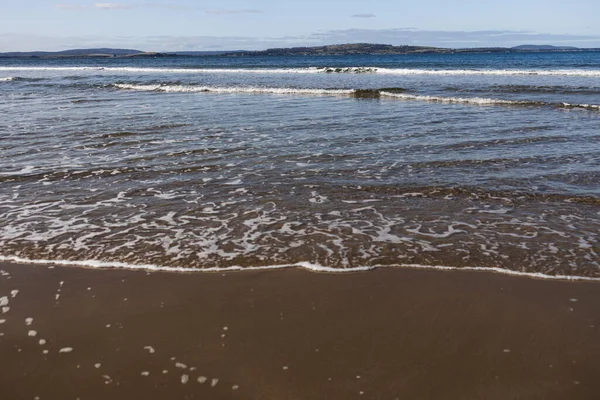 Tazmanya 'da el değmemiş bir sahil derin mavi okyanus ve Güney Hobart' ta koyu altın kum
