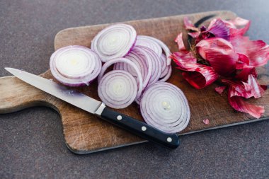 Basit gıda malzemeleri konsepti, kırmızı soğan ya da İspanyol soğanı mutfak tezgahının kırsal ahşap kesim tahtasının üzerinde halka şeklinde doğranmış.