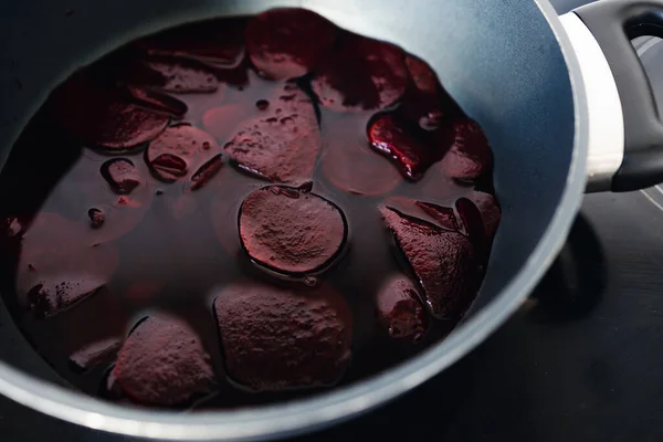 simple food ingredients concept, beetroot slices and juice in pot on kitchen stove top getting cooked